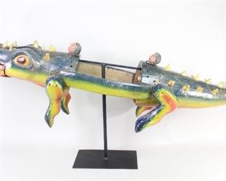 Lot 145: Carved Wood Alligator Body Mask,Mexico Folk Art Sculpture. Alligator body mask from Guerriro Mexico, used in the Danza de los Pescados (Fish Dance). Gorgeous alligator full of life and character is carved from wood with rich polychrome decoration, and an opening in the center for wearing as a mask. Legs are attached with twine and there is a human head on either side of the body opening. Mounted on a black metal stand for display. From the collection of Barbara Porter & Robert Wincuinas.

Dimensions are 22 in h x 13 in w x 53 in d. Condition is good with wear to the paint and patina. Please call or email for a detailed condition report.