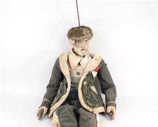 Lot 273: 19th C Early European Mechanical Puppet Marionette. A 19th century marionette puppet that could possibly have been made as early as 1700-1800s. A bearded man, made of wood with light stuffing with jointed knees and arms. Glass eyes. Wearing potentially Italian or Russian style clothes and hat, though they are not original to the puppet. Long metal hook attached to the head. From the collection of Barbara Porter & Robert Wincuinas.

Dimensions are 36 in h x 21 in w x 9 in d. Condition is fair. Wear throughout. Paint chipping and fading. Scratches. Clothes are in rough shape and are moth eaten. Please call or email for a detailed condition report.