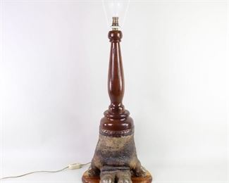 Lot 307: Victorian Hippo Foot & Brass Lamp. This curious large table light is definitely not your ordinary lamp. Body of the lamp is made from the foot of a hippopotamus, mounted on a wooden base, with a turned wood stem holding the light socket. Top of the foot is finished with beautiful hammered brass.
Dimensions are 33 in h x 13.25 in w x 10 in d. Condition is good with minor wear to the base and surface wear to the foot. Please call or email for a detailed condition report.

