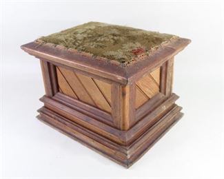 Lot 339: Woven Top Upholstered Wooden Heavy Foot Stool Pedestal. Appears antique, with aged nails and varnish on decorative trim over diagonal beadboard side panels. Top raised upholstered seat has a leaf pattern dominated by various shades of green. Inside appears to be filled with something to provide weight, allowing this piece to be used as a display base or pedestal.

Dimensions are 11 in h x 15 in w x 12.25 in d. Condition is good, with some wear and fraying around edges of fabric. Please call or email for a detailed condition report.