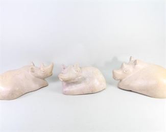 Lot 343: 3 Kenyan Carved Soapstone Rhino & Hippo Sculptures. A set of three sculptures; two Rhinos and one Hippo, carved in a light tan colored soapstone with beautiful grain, polished perfectly smooth. All three animals have a little bird perched somewhere on their body. Slightly hollowed out underneath. From the collection of Barbara Porter & Robert Wincuinas.

Dimensions for the largest are 7 in h x 14.25 in w x 7.5 in d. Dimensions for the smallest are 5.75 in h x 10.75 in w x 7.5 in d. Condition is good. Surface wear and scuffs throughout. One has been repaired on the back. Please call or email for a detailed condition report.