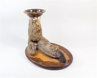 Lot 379: Mounted Ostrich Talon Foot Taxidermy Ashtray. Antique Ostrich foot taxidermy, made into an ashtray and mounted on a wooden base. The wooden base is two-toned, with the lighter top layer roughly following the outline of the foot, while the base is darker. The ashtray itself is made in a matching dark wood.

Dimensions are 8.25 in h x 9.75 in w x 6 in d. Condition is very good. minor wear, mostly to wood base. Stains and scuffs. Please call or email for a detailed condition report.
