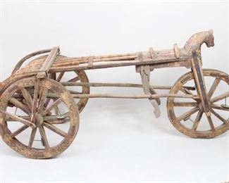 Lot 393: Wonderful Antique Colonial era wooden market wagon from India has a carved horse's head at the front, and painted polychrome floral details throughout. Wooden wheels have iron bands around the outside. Original body with a newer support built for front wheel and horse. Wonderful character & patina. Acquired in India in 1982. From the collection of Barbara Porter & Robert Wincuinas.

Dimensions are 67 in h x 33 in w x 31 in d. Condition is good with wear to the wood & paint. Please call or email for a detailed condition report.