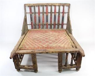 Lot 402: Low Colonial Style Market Chair from India w/Woven Seat. A low, deep colonial era market chair from New Delhi with back, sides and feet in turned wood. Joints are reinforced with metal and supports are added for the back. Painted in red, blue and green. Woven seat in red and tan. Acquired in the 1980s, New Delhi, India. From the collection of Barbara Porter & Robert Wincuinas.

Dimensions are 26.5 in h x 21 in w x 27 in d. Condition is fair to good. Surface wear throughout. Paint is worn, chipped and faded. Rust to metal. Two spindles are missing in front. Fragile. Please call or email for a detailed condition report.