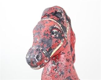 Lot 418: Red Painted Concrete Horse Head Knight Hitching Post. Decorative freestanding hitching post in the form of a horse's head on a column, with a shape reminiscent of a giant knight chess piece. Red paint has worn to a nice weathered patina.

Dimensions are 41 in h x 12 in w x 12 in d. Condition is fair, with paint loss and chips, damage and cracks at base. Please call or email for a detailed condition report.