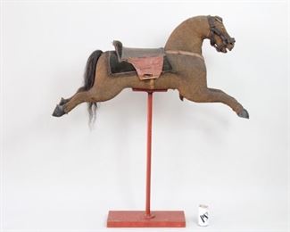 Lot 419: Antique Rocking Horse Mounted on Stand. Beautifully detailed horse in covered in brown fabric, with a leather saddle, corduroy saddle blanket, carved wooden hooves, a horsehair tail and even tiny metal horseshoes. Display as sculpture on its red stand. Has wonderful character. and patina. Acquired in Vermont in the mid 1970’s. From the collection of Barbara Porter & Robert Wincuinas.

Dimensions are 45 in h x 51 in w x 8 in d. Condition is good with wear to fabric. Please call or email for a detailed condition report.