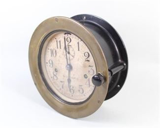 Lot 433: Seth Thomas US Navy Maritime Nautical Ships Clock & Key. Marked Seth Thomas on front and embossed serial number R-20704 on rear, suggesting manufactured circa 1907. Beautiful calligraphic serif type in numbers on heavily mottled face. This model had a double-wind operation, though this unit has not been tested. Round brass front trim and black plastic housing. Similar unites were widely used by the US Navy.

Dimensions are 7.75 in h x 7.75 in w x 3.75 in d. Condition is good, with minor wear to metal surface and inner casing, staining and spots throughout, consistent with age and probable onboard use. Please call or email for a detailed condition report.