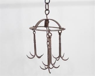 Lot 453: Primitive Wrought Iron Hanging Butcher Kitchen Hooks. This solid hanging piece has four arms, one central and three flanking it, each terminating in 4 upturned hooks. Subtle details like the cupped crown head and forged twist at the midpoint of each hook add a touch of flair. Could hold a variety of pots, pans, utensils, or things that were recently alive. Use in your retail floor, kitchen, barn, basement, or dungeon, however you imagine. Topped with a matching S-hook and chain for easy installation.

Dimensions are 23 in h x 12 in w x 12 in d. Condition is very good, with minor surface wear and rust throughout. Please call or email for a detailed condition report.