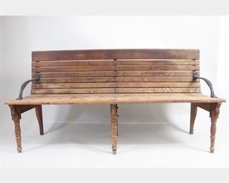 Lot 298: Railroad Train Depot Wood & Iron Bench w/Turned Legs. Handsome and heavy bench has a wooden frame with wooden slats for the seat and back, and cast iron arms. An unusual feature is the 3 turned legs on the front. Wonderful bench for your porch, entryway or even a waiting area for a business. Dimensions are 33.25 in h x 64 in w x 19 in d. Condition is good with surface wear, some stain spots, discoloration and wear to edges. Please call or email for a detailed condition report.