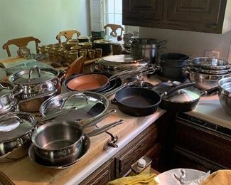 A large section of pots and pans including a set of Kirkland professional pans, Heckel skillets, stainless strainers and mixing bowls several pieces of vintage Paul Paul Revere stainless with copper bottoms. A beautiful selection!