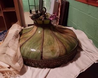 Vintage Slag hanging glass fixture estimated from early 1900.   Colors are green, cream and brown swirl  glass, which is incased in a heavy cast filigree decorative frame.  Wired for two light bulbs with optional on/off turn switches.  Built in hook for hanging.    One small glass piece is missing at top crown, but not repair is possible.
 Very Heavy!