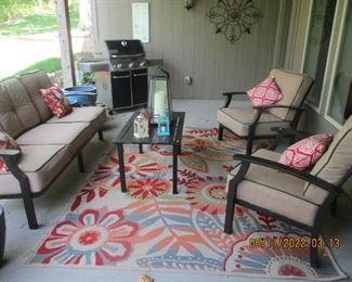 Cushioned patio set with Weber grill and outdoor carpet and large planters