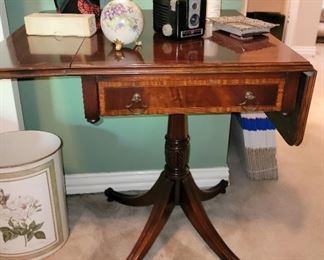 Mahogany drop leaf side table with decor including vintage camera
