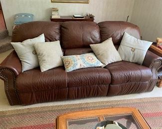 Brown faux leather reclining sofa, assortment of throw pillows