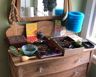 Old oak dresser with mirror,  blue bottle brush lamp, fun sunglasses, old advertising hangers 