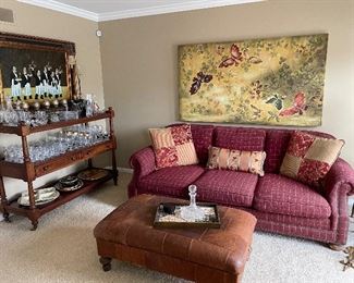 Red plaid 3-cushion couch with nailhead details; Leather ottoman; butterfly canvas; 3-tier sideboard by Ralph Lauren; glassware:  Ralph Lauren and Waterford; French Waiters - framed artwork