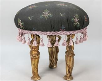 9	Art Nouveau Figural Footstool	"Art Nouveau figural footstool. Early 20th Century. Upholstered black fabric with fleur-de-lis, lavender tassels, three female figural caryatid supports. All three supports are slightly loose, original label is missing. 
13"" H x 13"" diameter"
