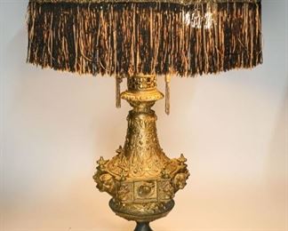 10	Renaissance Revival Metal Table Lamp	Renaissance revival metal table lamp with slag glass shade. Symmetrical foliate decoration with six heads around the circumference of the lamp. Tassel pull chains. Slag glass shade with fabric tassels and metal foliage applique. 23" H (from base to shade) x 17" shade diameter. Wear to paint of the metal base.
