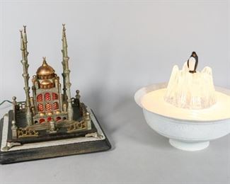 25	Two Figural and Architectural Novelty Desk Lamps	"Two figural and architectural novelty desk lamps. 20th Century. An architectural form mosque lamp, consisting of cast metal on wooden base. Lamp is marked Dilekis on base.  A penguin on iceberg figural lamp, with frosted glass sitting on metal chassis. Both lamps have been tested and work. Rust and oxidation on mosque lamp.
Mosque lamp measures 11"" H x 9 1/2"" L x 9 1/2"" W
"
