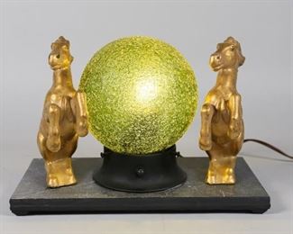 33	Art Deco Horse Table Lamp	Art Deco horse table lamp. Gilt metal horses and green crackle glass shade. Mounted on a composite base. 11 3/4" L x  5 3/4" W x 7 3/4" H. Scuffing to the base. Crazing and chips to gilt paint.
