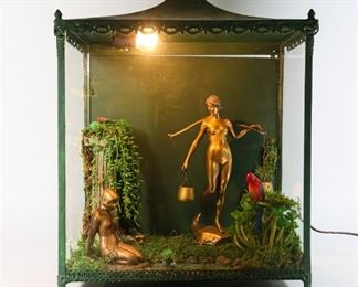 52	Art Nouveau Nude Bronzes Outsider Art Display	"Art Nouveau nude bronzes outsider art display. American, Late 20th Century. A Victorian style display cabinet designed by Robert Kayton (label on back) containing two female nude bronzes, one kneeling by a small pond, the other carrying water pails, with faux decorations of vines, plants and grass. Illumination tested and works. 
19"" H x 14"" L x 9"" W"
