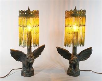 81	Pair Figural Cast Metal Gargoyle Dog Lamps	Pair of figural gargoyle or winged dog cast metal lamps. With beaded shades. Each 15 1/2"H to finial. Some wear and scratches to patina, wires on both plugs exposed.
