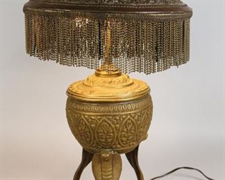 100	Gilt Brass Urn Lamp with Cobras	"Gilt brass urn shaped lamp upon 3 cast brass cobras. Art nouveau style brass shade with brass bead tassels. 
25"" H. Some tassels missing. Gilt worn above 1 cobra, crack and chip to shade.
"
