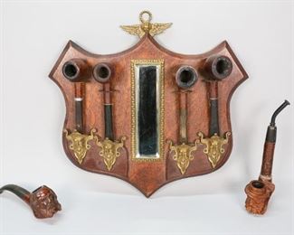 129	6 Estate Pipes and Pipe Display Holder	"6 Estate pipes and pipe display holder with mirror in center and cherub hanger. Pipes include: Grecian Briar, Kaywoodie (69) Flame Grain, Knickerbocker Imported Briar, Webco Imported Briar, carved man with hat and beard marked Kemperling Austria, carved man with goatee marked Made in Italy Imported Briar. 

Longest: 7 1/4"". 
Display: 13 1/2"" H x 13"" L."
