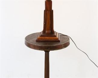 141	Arts & Crafts Wood Table Lamp and Stand	Arts & Crafts tiered wood lamp, wood shade with metal riveting to the top. Wood stand with metal riveting to the edge. Figural metal leaf collar. Stand marked with a M within a circle on the base. 53 1/4" H (from base of stand to top of lamp). Indentation to top of stand. Loss to paint on shade. Splitting of wood on shade.
