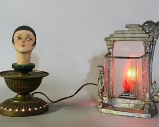 144	2 Art Deco Lamps	"2 Art Deco lamps. Painted composite lady's head mounted on a brass stand. Painted metal fireplace lamp with beaded curtains, frosted glass panel shade. 
Fireplace lamp: 5 1/2"" x 4 1/2"" x 9 3/4"" H. 
Wear to silver paint on edges of fireplace lamp. Wear to paint on ladies head. Scuffing to brass base."
