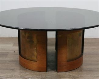        296	Danish Modern Glass Cocktail Table	"Danish Modern glass cocktail table. Mid 20th Century. Circular smoked glass top, two demilune form bases with black leather, teak and copper inserts. Heavy scratches to glass, some loss to wood on bases. 

15"" H x 36"" diameter"