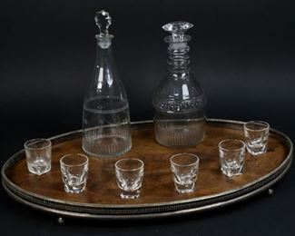        452	2 Glass Decanters, 6 Shot Glasses & Walnut Tray	"Walnut serving tray with silverplate rim. 2 glass decanters and 6 glass shot glasses. Tray: 21 3/4"" L x 14"" W. Largest decanter: 10"" H. Scratches to the underside of tray and decanters. Chips to the stopper of 1 decanter. Chips to rim of 2 decanters. Bubbles to the body of both decanters, interior crack to the neck of 1 decanter.
"