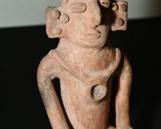 Pre-Columbian seated Nayarit deity figure.  The Nayarit adorn their bodies with jewelry such as the necklace around his neck and earrings in his ears. 