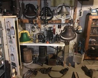 large bells w/ their yoke and mounting brackets and a number of smaller bels. NOTE: the John Deere bell on the left, the multi sleigh bell string in the upper middle, also pictured are pullies, nail keg, hand pumps, sausage stuffer, heat grate, tree augar, right of center shows a drive-in car speaker,... hidden is a 1937 license,