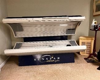 Sunstar tanning bed with tanning accessories, laundry basket, plant stand