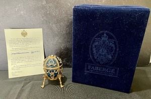 Fabulous Faberge Millennium Egg #745 measuring 4 inches tall including the stand. Inside the egg is a golden earth trinket box and inside of that is a small "2000" pin. One on the legs on the stand needs repair. 