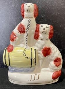 This vintage Staffordshire figurine measures 8 inches tall. A very nice moulded and painted Staffordshire group of two spaniel; one is chained to a barrel. Item in very good condition. 