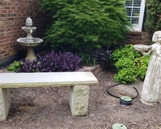 Stone outdoor bench and statues and bird bath