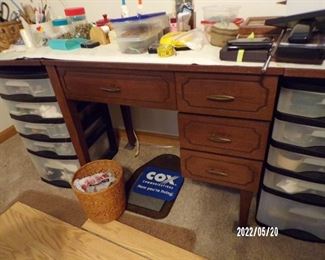 think is a sewing machine cabinet used as a desk or crafting area, lots of sewing notions