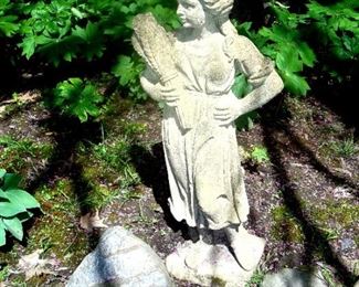 One of two  cement figures of young girl with sheaf of wheat.