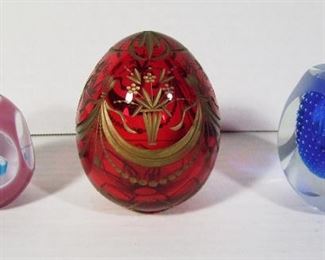 Lot 282   3 Handblown glass Paperweights including: cut ruby egg form signed “St. Petersburg, Russia”, 3 ¾” h.  Pink cased and cut egg form with Millefiori interior, 2 ¼” h. Cobalt cased egg form w/controlled bubble and cut sides, 3” h.  Cond: No damage found.     $35 - $55