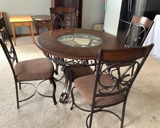 Dark wood and black decorative wrought iron round dining table, with glass in center of table top, some wear and scratches on the table surface. Also has a small lower shelf under the table. Comes with (4) matching chairs with cloth cushion seats, fabric shows some wear, lazy Susan, glass sugar, salt & pepper shakers and doily. Table H30"x W 45", chairs H 39.5"x W 19.5"x D 24".
