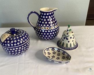 Colorful Polish pottery that includes a 7" pitcher (shows crazing on the bottom), 5" covered apple shaped bowl, spoon rest, and 4" Holiday Bell. All items are stamped with the exception of the Holiday Bell.