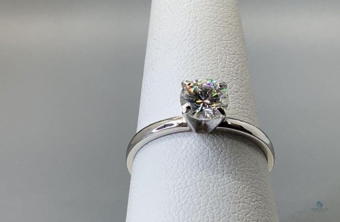 Stamped 10k white gold custom wax and cast solitaire ring with a comfort fit shank with a rhodium plated finish, size 7.5.` One prong set round cut moissanite, 6.15x3.54mm, 1.12gtw, with appraisal certificate included.