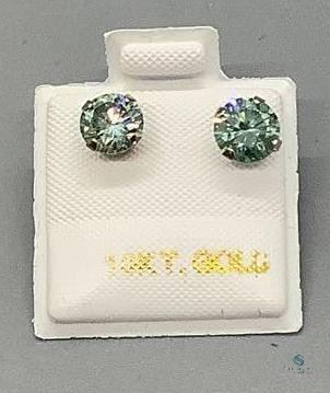 One pair stamped 10kt white gold hand assembled stud earrings with friction posts with a rhodium plated finish. Two basket set round cut moissanites, measuring 6.19x3.05mm, light bluish green, 0.68gtw, with appraisal certificate.