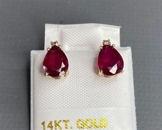 One pair stamped 14kt white gold combination cast and assembled stud earrings with a rhodium plated finish. Two basket set pear cut natural rubies, 7.20x 4.85x2.45mm, and two prong set round brilliant cut diamonds, 1.45x1.22mm. 1.30gtw earrings. Appraisal report included.