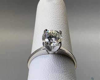 One stamped 14kt white gold cast solitaire ring with a cathedral shank with a rhodium plated finish. One prong set round cut moissanite measuring 6.79x4.0mm, size 6, 2.26gtw.,certificate of appraisal included.