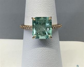 One stamped 10kt yellow gold combination cast and assembled ring with a cathedral shank with a high polish finish. One prong set emerald cut natural emerald-colombia, 9.55x9.18x5.70mm, and sixteen shared prong set round brilliant cut diamonds, measuring 1.40x0.84mm, 2.97gtw, size 6.5. Appraisal certificate included.