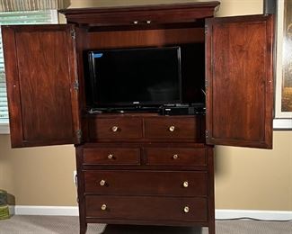 STANLEY FURNITURE ARMOIRE | Dark wood dresser cabinet with two checkered doors with contrasting woods opening to reveal a TV / entertainment console or optional use as a vanity with two interior drawers, all over a lower section with two half drawers over two full-width drawers; 49 x 72 x 27 in.
