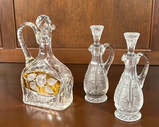 (3pc) CRYSTAL VESSELS | A pair of cut crystal oil and vinegar bottles with matching stoppers (h. 7-3/4 in.) and a medium sized crystal decanter with etched floral motifs and amber glass accent (h. 9 in.) [repaired handle]